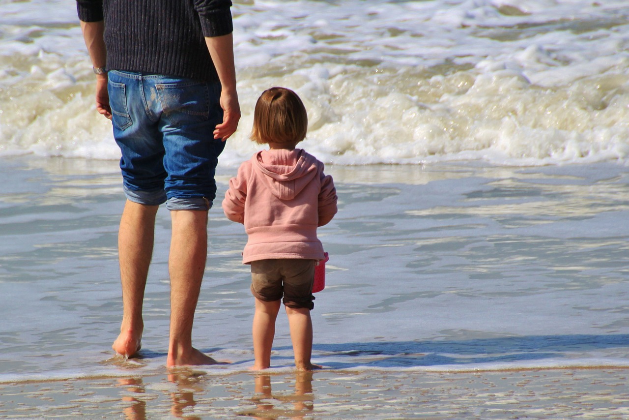 Child and dad standing by the sea